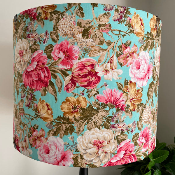 Large drum fabric lamp shade with flowers on blue background, unlit. 