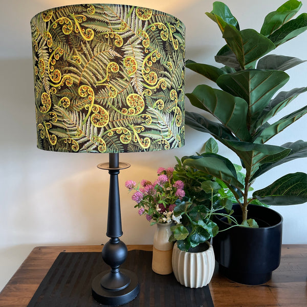 Large drum hand crafted lamp shade with green fern fabric, close up, lit.