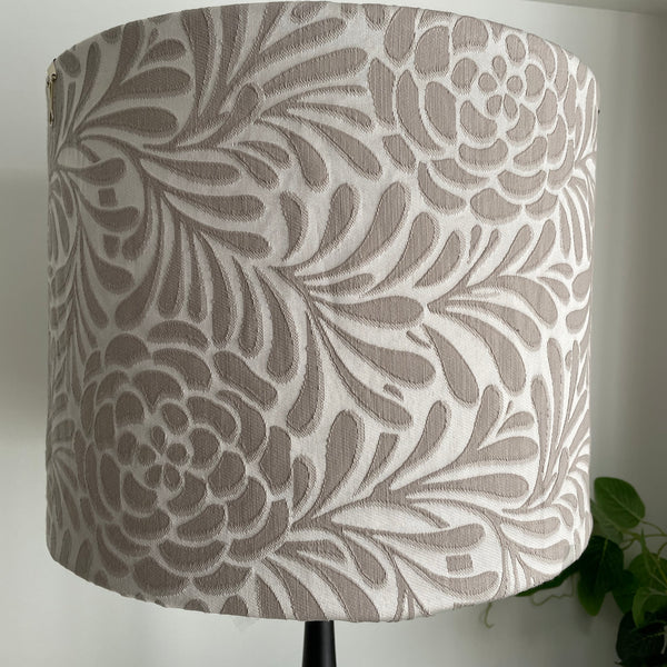 Large fabric light shade with large taupe flowers and foliage on silver grey background, unlit.