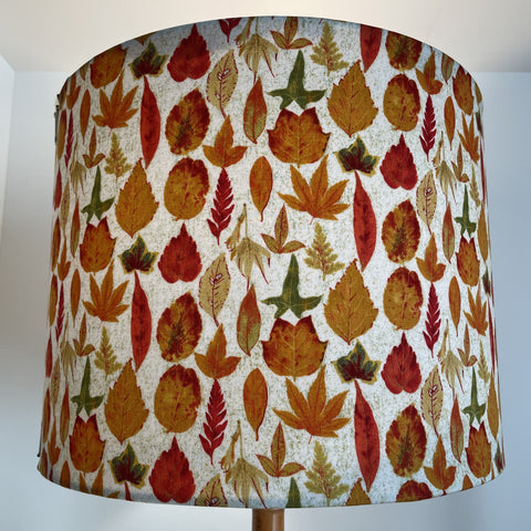 Large handcrafted fabric lamp shade with autumn leaves fabric, lit.