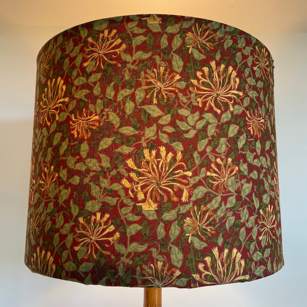 Large tapered handcrafted lampshade with William Morris honeysuckle deep red fabric, lit.