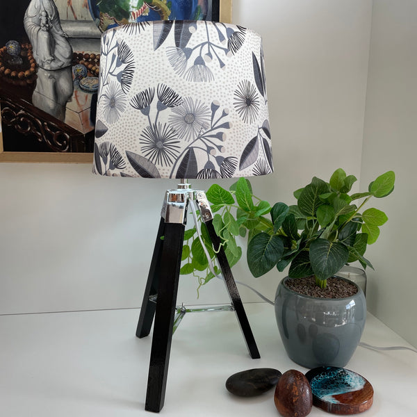 Medium tapered lampshade in eucalyptus blossom fabric on gloss black tripod stand | handcrafted | lit