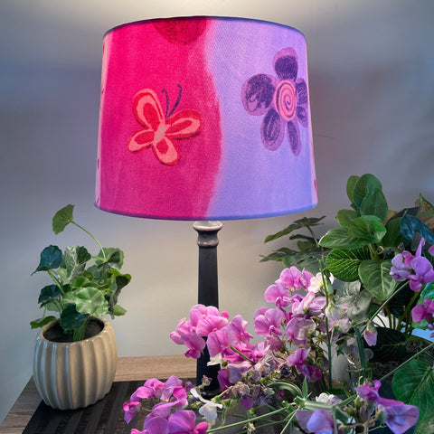 Medium tapered handcrafted fabric lampshade in a variety of pinks with flowers and butterflies.