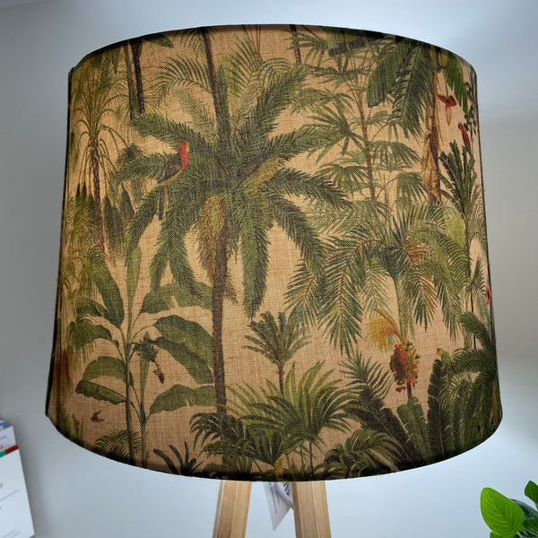Close up of handcrafted lampshade in jungle palm fabric on natural wood lamp base.