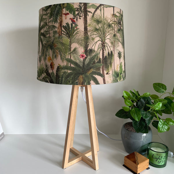 Modern wood table lamp with handcrafted lampshade in jungle palm fabric, unlit.