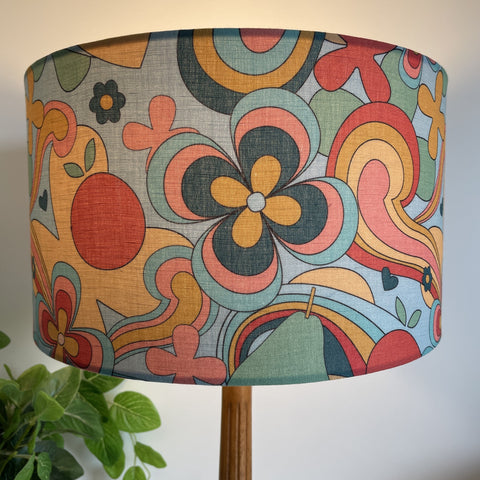 Multi-coloured medium fabric lamp shade in 60's style, lit.