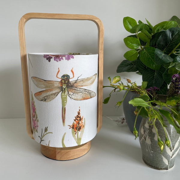 Natural timber table lamp with dragonfly fabric lampshade, unlit.