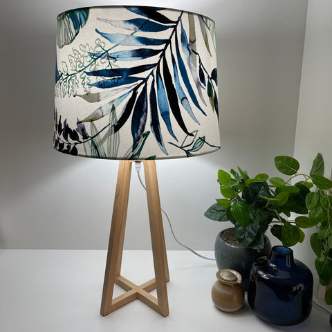 Natural wood table lamp with handcrafted fabric lampshade, lit.