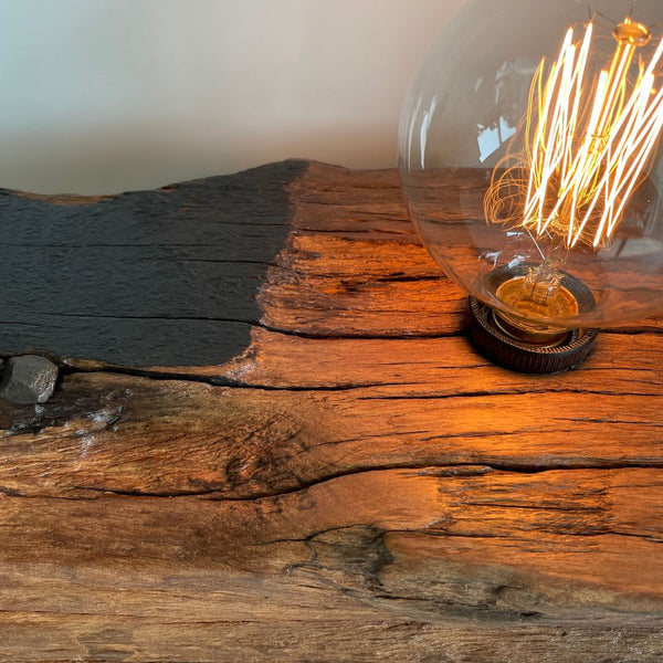 Original tar markings, and nail with edison light bulb on wharf timber table lamp, close up.