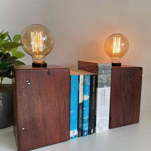 Pair of wooden reclaimed table lamps, handcrafted from old square telegraph post with retained original nails and additional edison light bulb, lit.