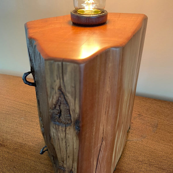 Polished grain of old totara post crafted into unique wooden table lamp. Close up of smooth polished top and side.