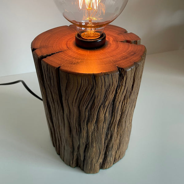 Round timber table lamp with front hole and polished top. Side view.