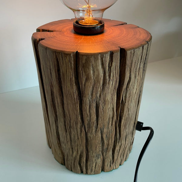 Round timber table lamp with front hole and polished top. Right side view.