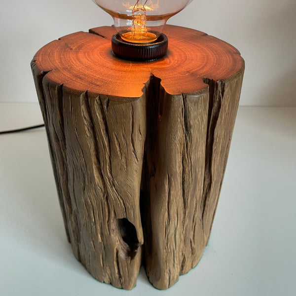 Round timber table lamp with front hole and polished top.