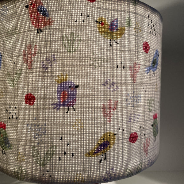 Small hand crafted lamp shade with sweet birdies on a white background lamp shade, lit, close up