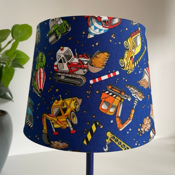 Small tapered hand crafted lamp shade with childrens' construction trucks fabric, unlit.