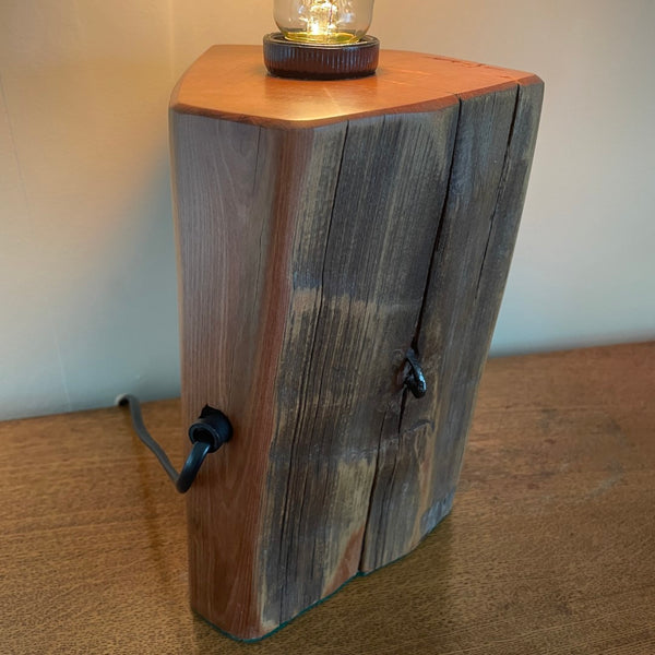 Timber table lamp, polished totara grain with original iron staples and lit edision light bulb.