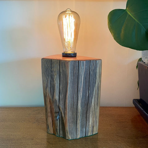 Timber table lamp, polished totara grain with original iron staples and lit edison light bulb.