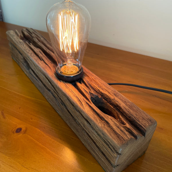 Eco-friendly table lamp made from recycled telegraph post, featuring vintage-style Edison light bulb