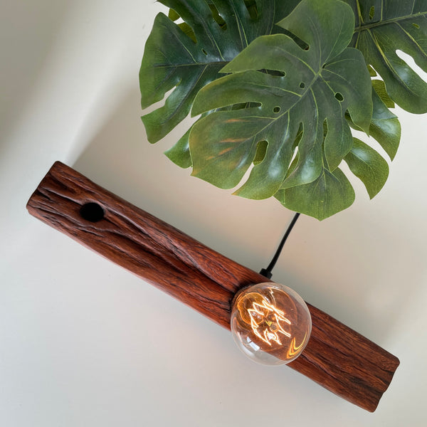 Wooden table lamp handcrafted from old telegraph post with edison bulb, lit.