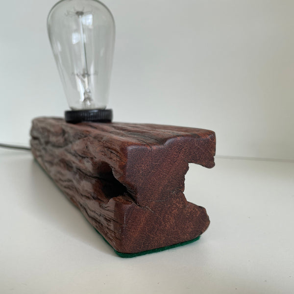 Rich brown polished end grain of wooden table lamp handcrafted from old telegraph post with edison bulb.